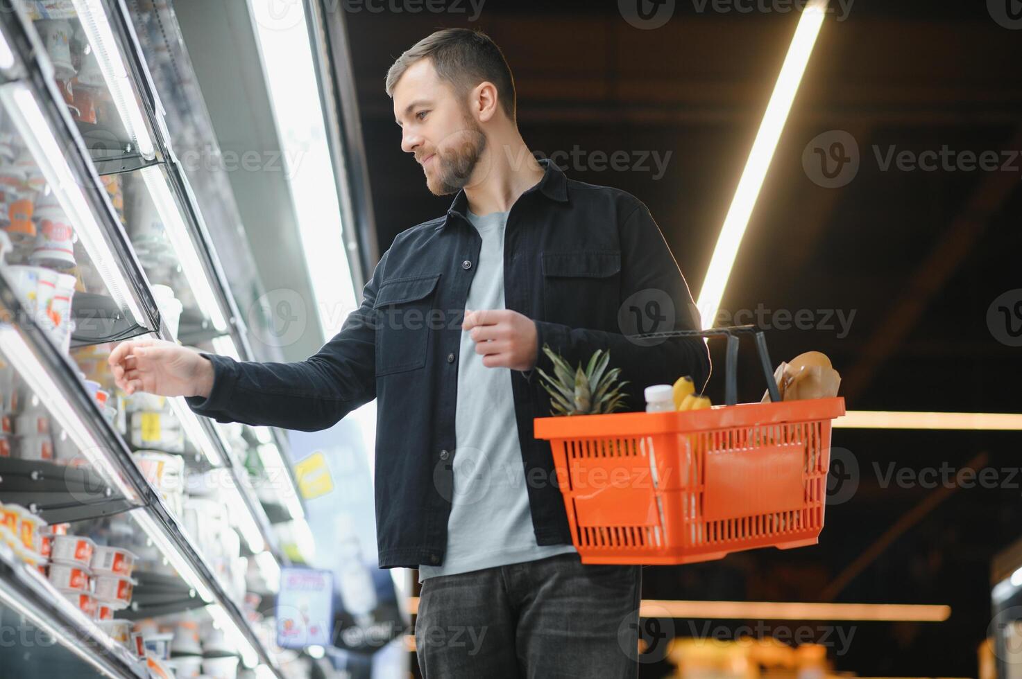 Portrait of smiling man walking with his trolley on aisle at supermarket. photo