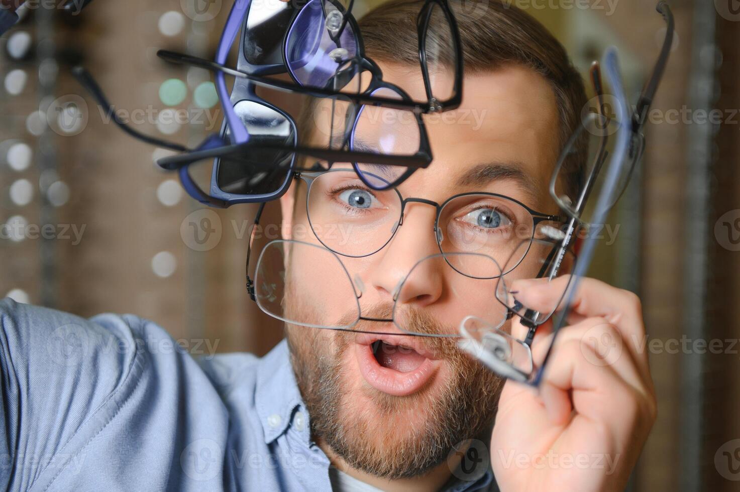 Young man choosing spectacles at optic shop photo