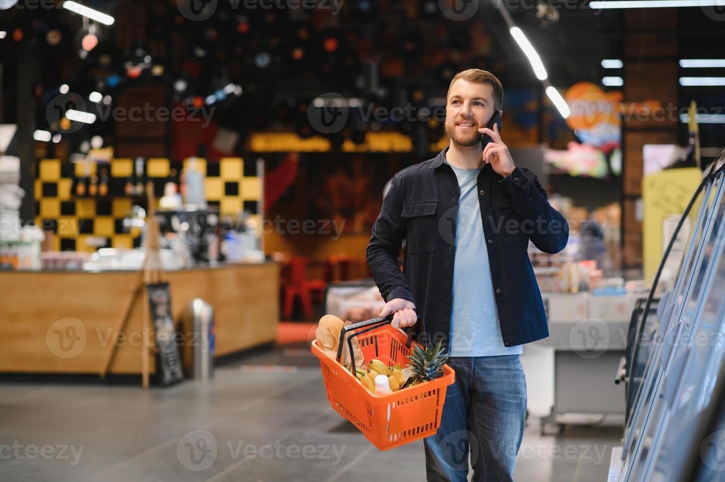 Customer In Supermarket. Man Doing Grocery Shopping Standing With Cart Choosing Food Product Indoors. Guy Buying Groceries In Food Store. Selective Focus, Copy Space. photo