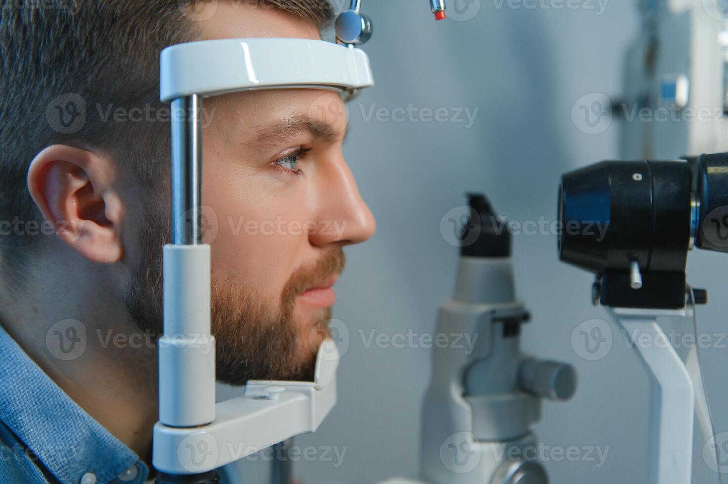 Handsome young man is checking the eye vision in modern ophthalmology clinic. Patient in ophthalmology clinic photo
