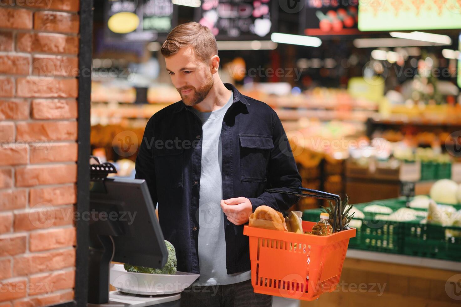 hermoso hombre comprando algunos sano comida y bebida en moderno supermercado o tienda de comestibles almacenar. estilo de vida y consumismo concepto. foto