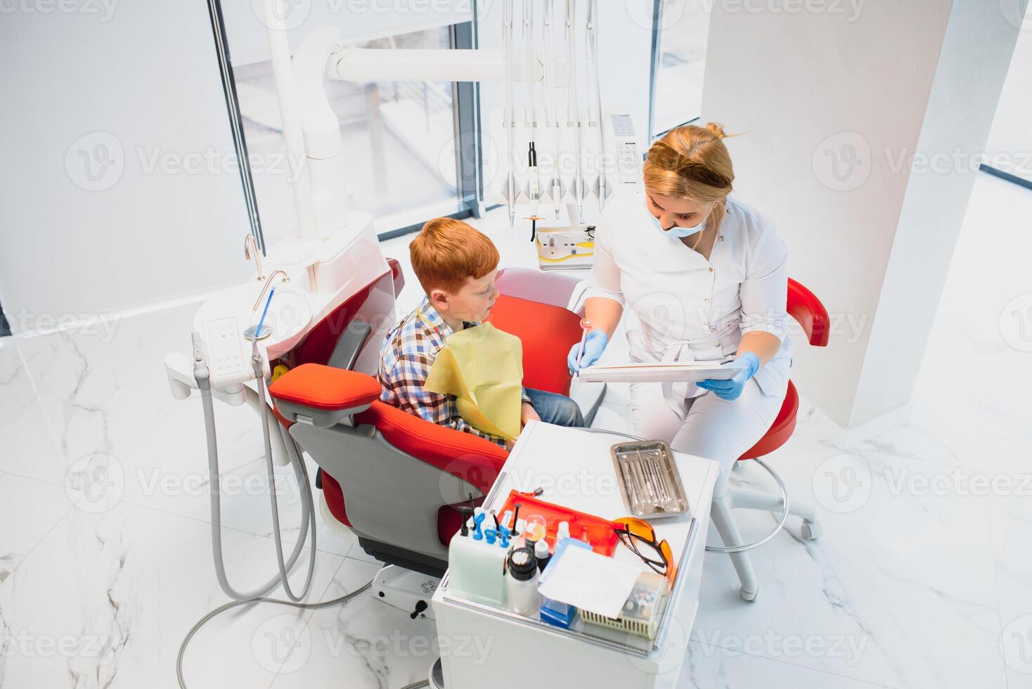 dentista vistiendo mascarilla. Pelirrojo niño dentista vistiendo máscara examinando linda chico foto