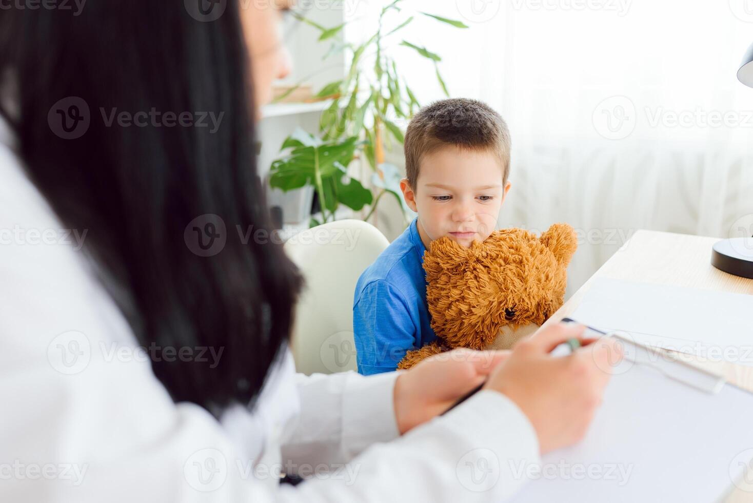 joven hembra psicólogo trabajando con pequeño niño en oficina foto