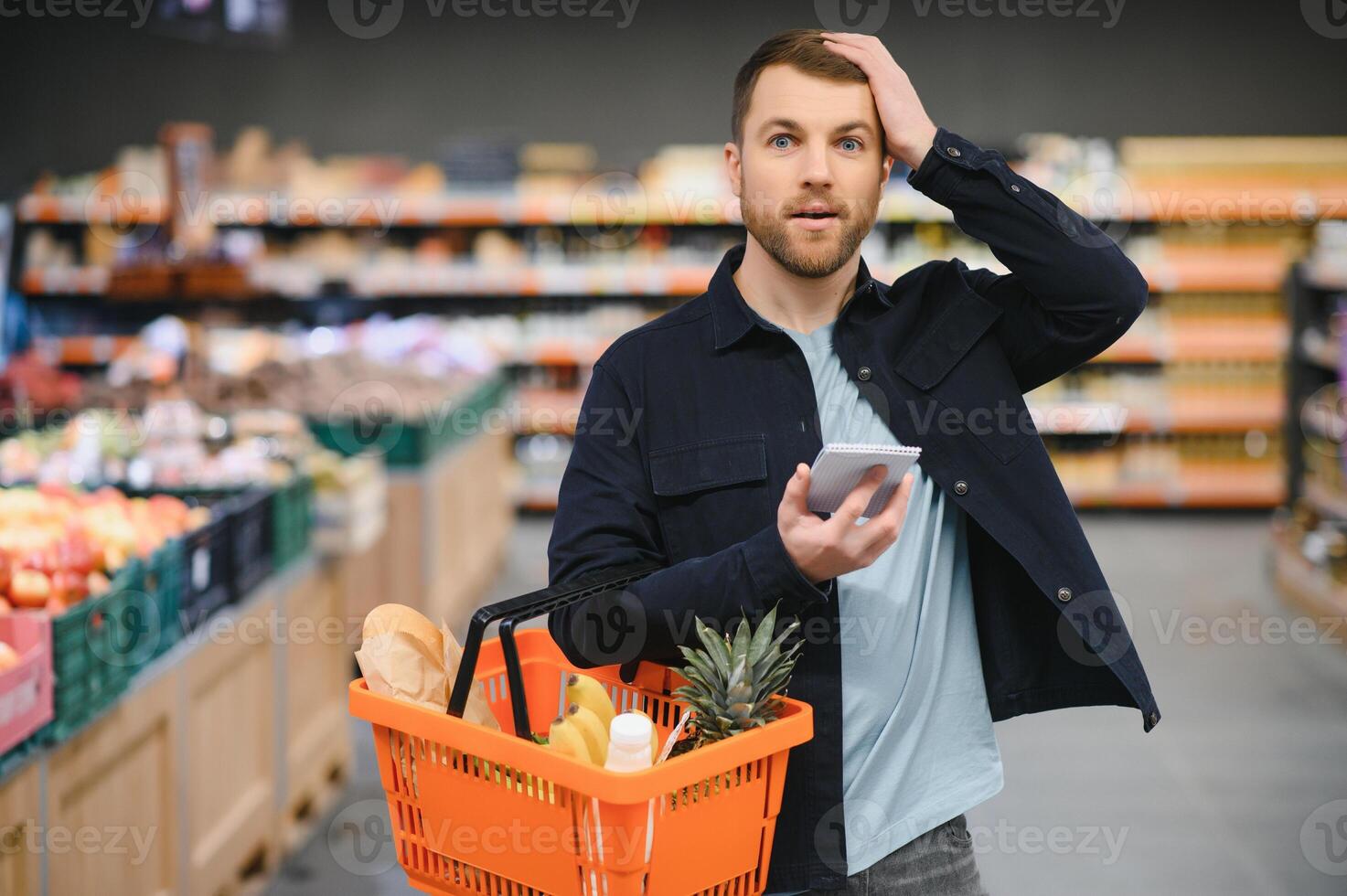 Young man buying groceries at the supermarket. Other customers in background. Consumerism concept. photo