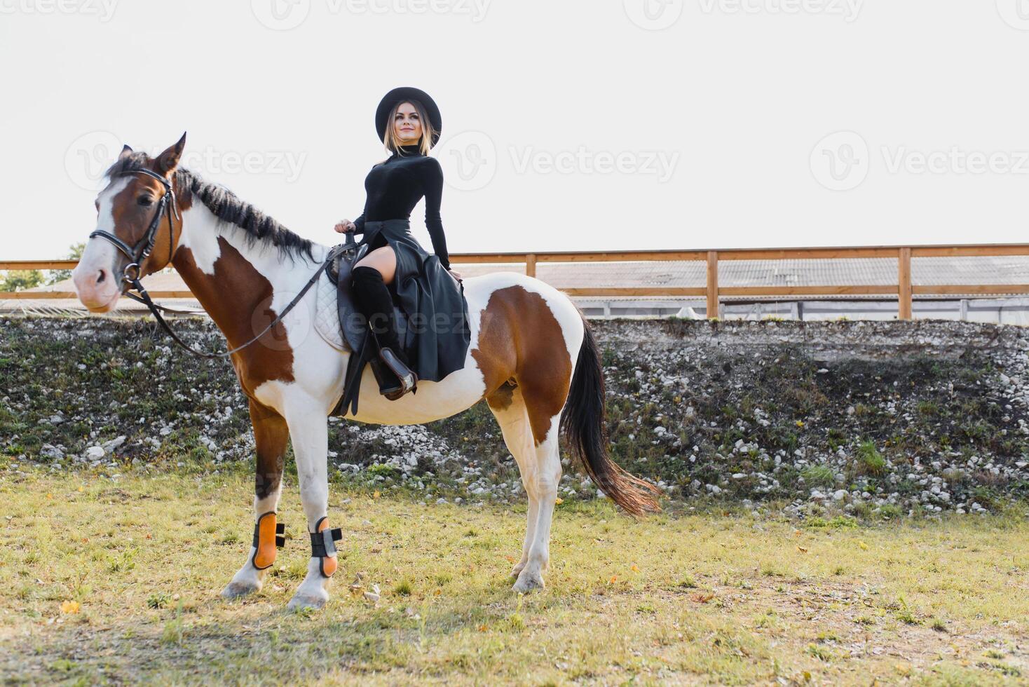 Happy fashionable young woman posing with a horse on the beach photo