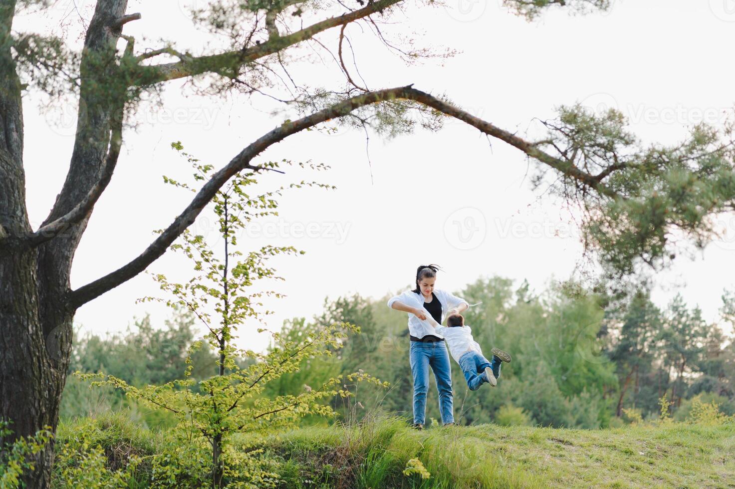 elegante madre y hermoso hijo teniendo divertido en el naturaleza. contento familia concepto. belleza naturaleza escena con familia al aire libre estilo de vida. contento familia descansando juntos. felicidad y armonía en familia vida. foto