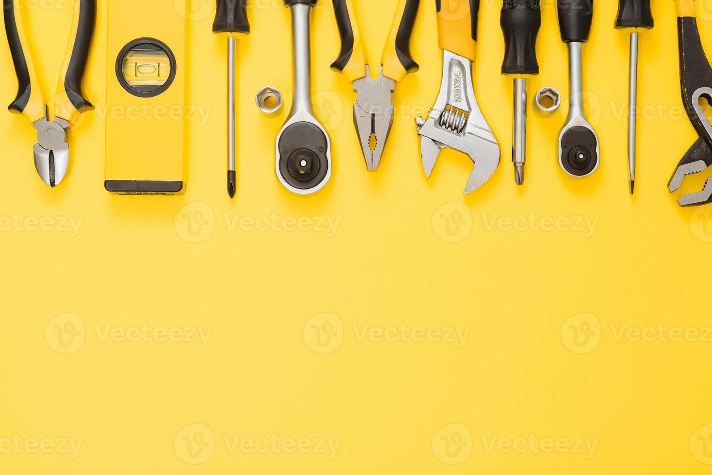 Yellow and black handy tools pilers and screwdriver isolated on yellow background. photo