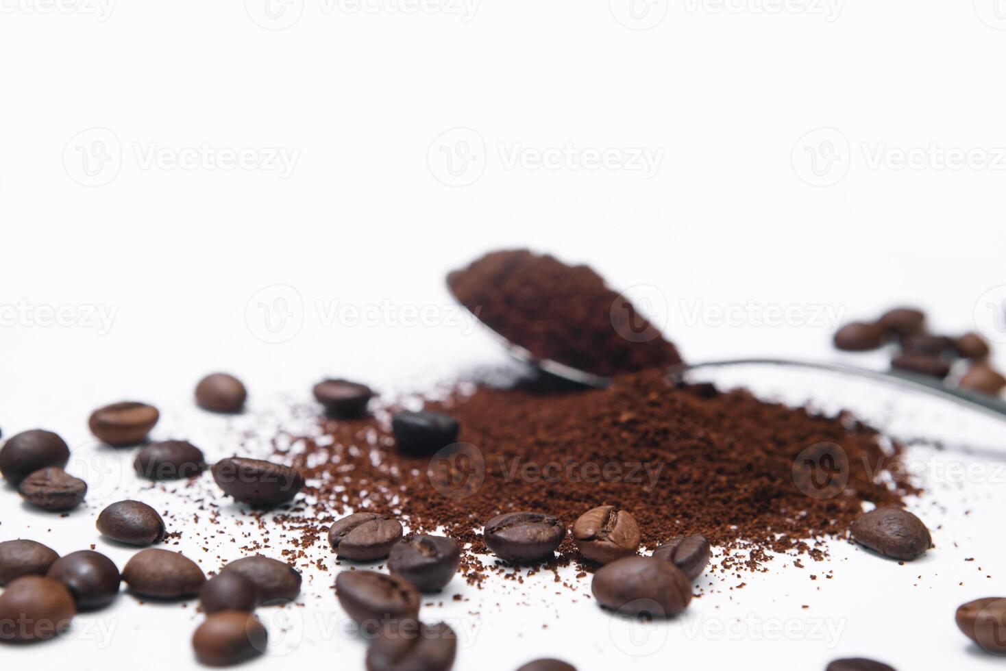 Grounded coffee in a spoon surrounded with beans isolated photo