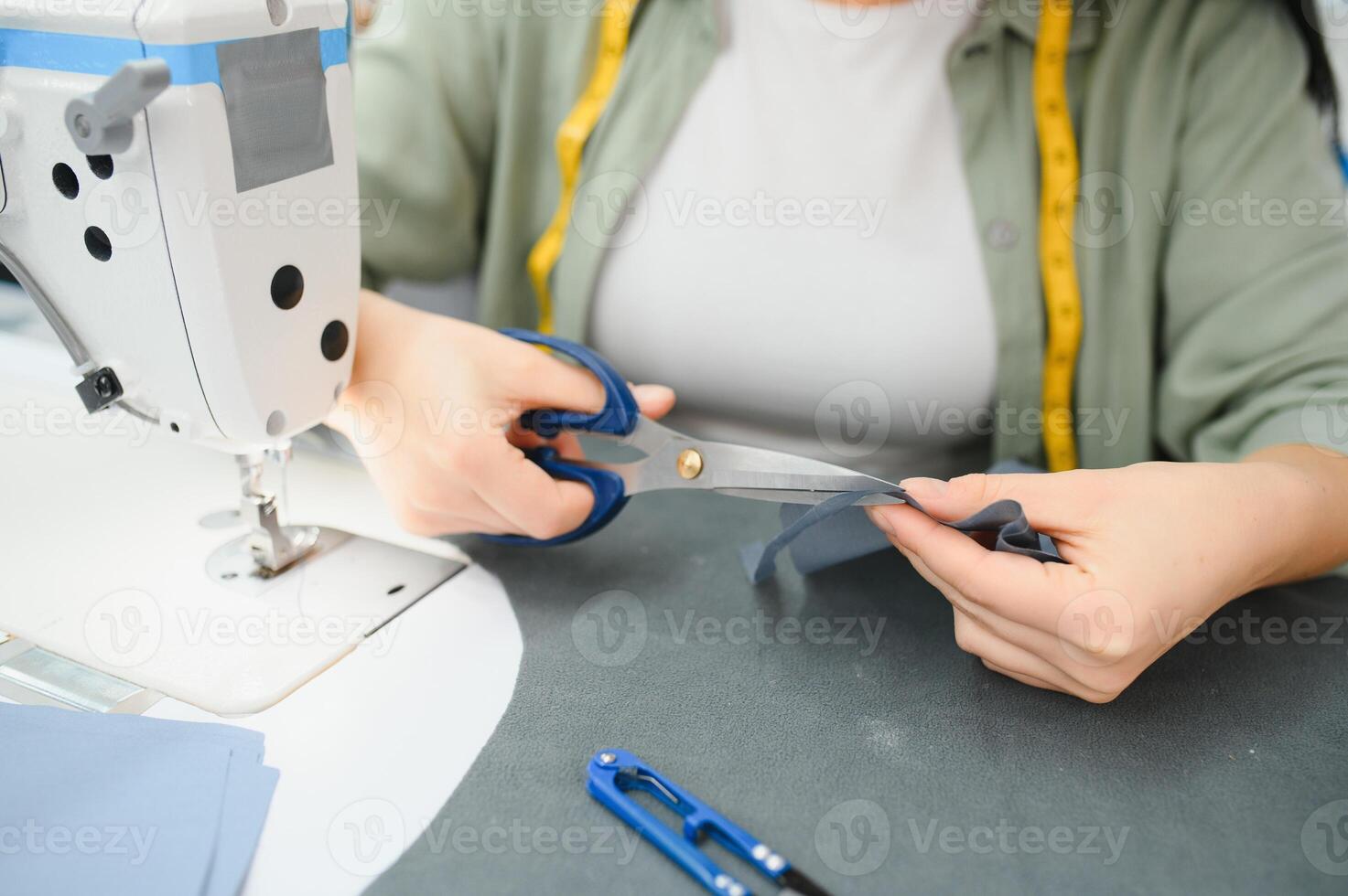 Portrait of a beautiful seamstress carrying a tape measure and working in a textile factory photo