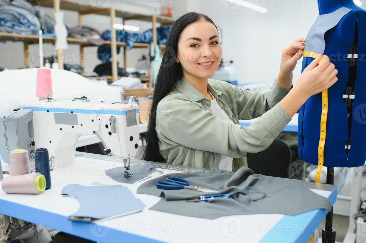 Seamstress at work. Dressmaker making clothes in modern studio. photo