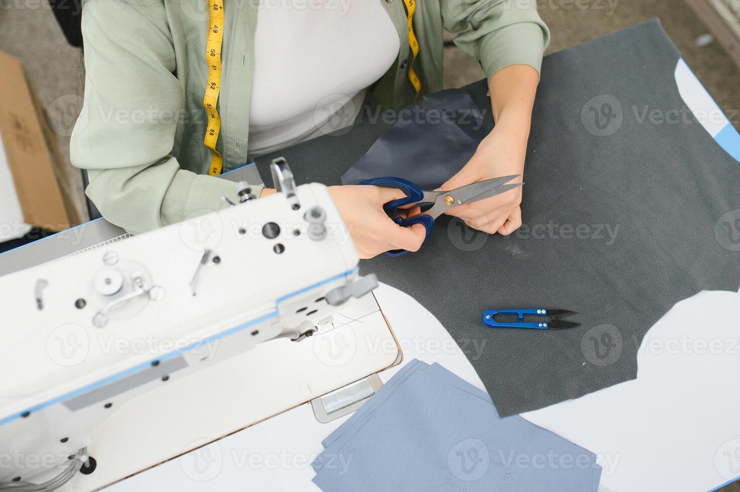 Portrait of a beautiful seamstress carrying a tape measure and working in a textile factory photo