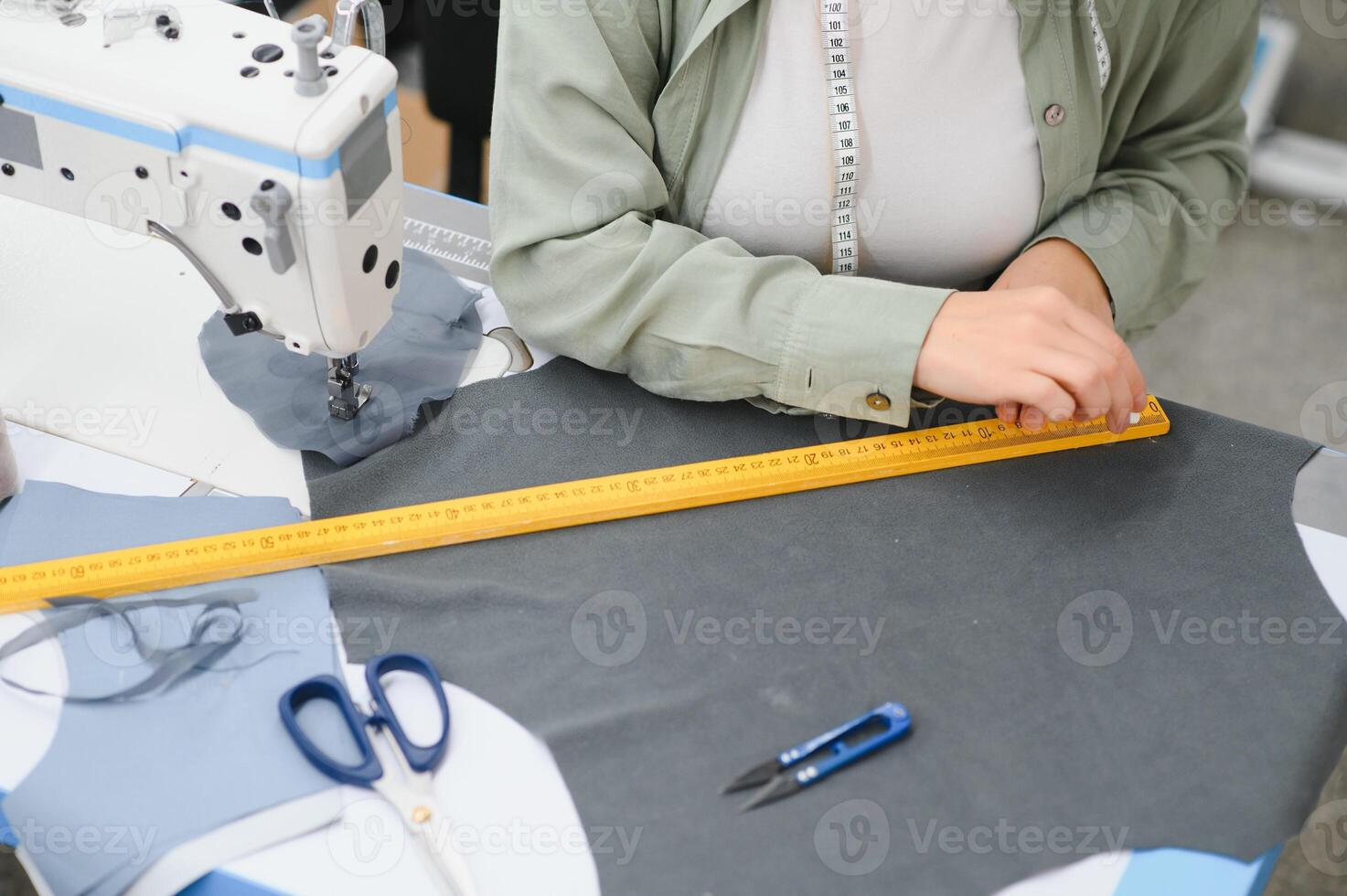 Portrait of a beautiful seamstress carrying a tape measure and working in a textile factory photo