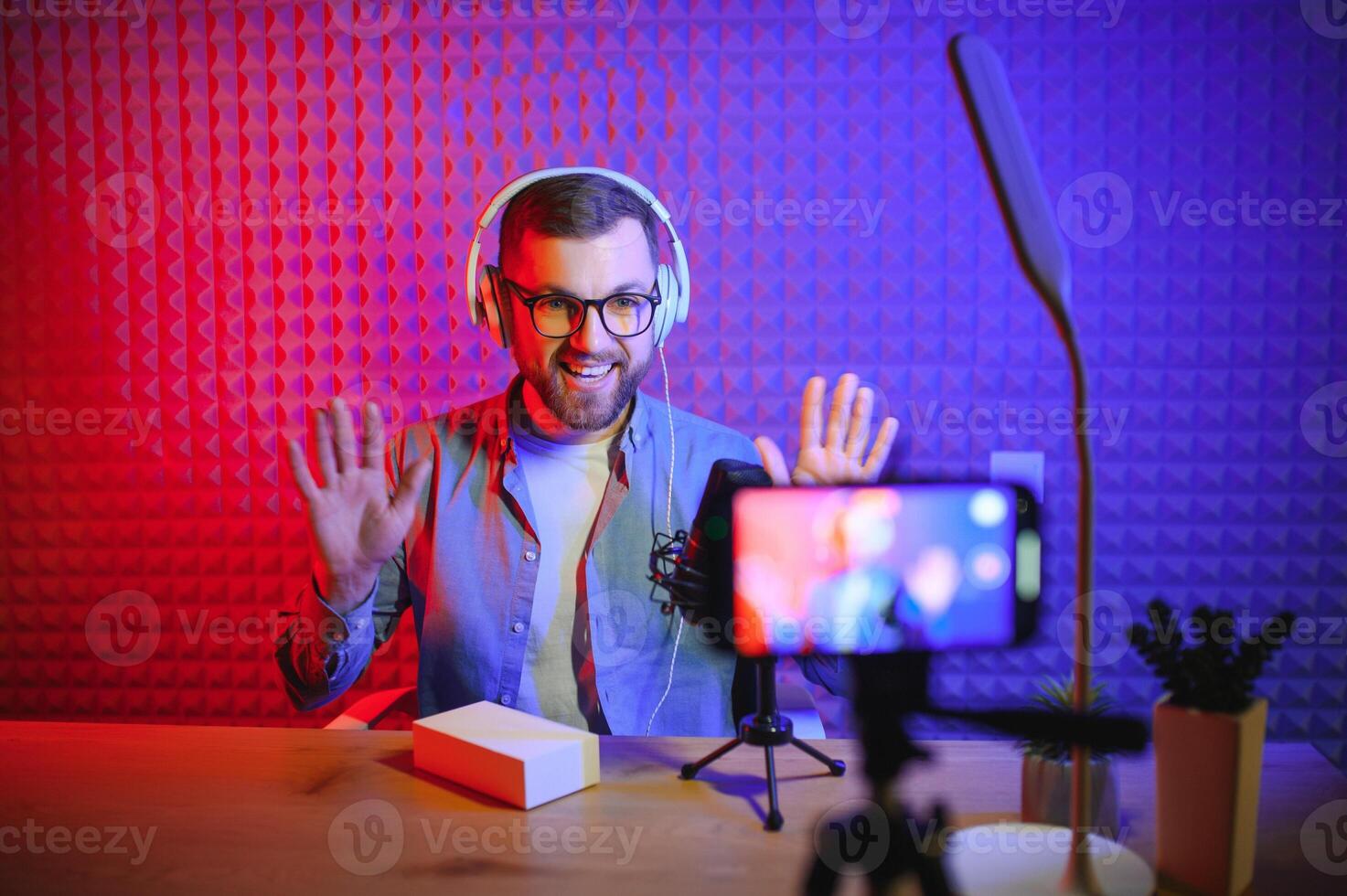 Young man recording or streaming podcast using microphone at his small broadcast studio. Content creator. photo