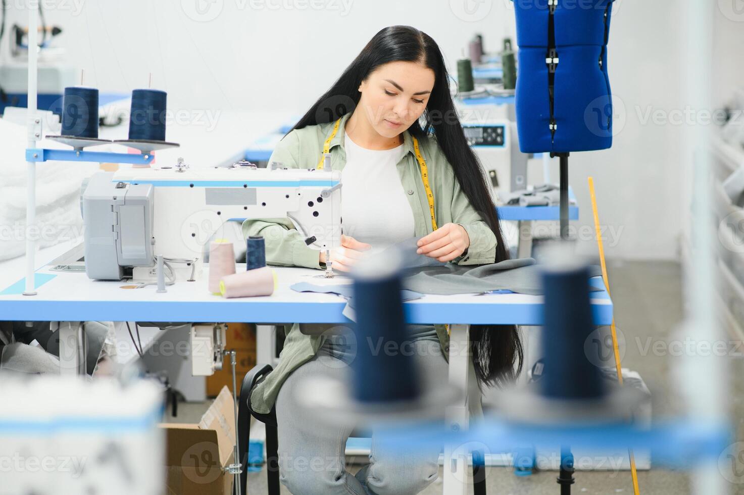 Young woman working as seamstress in clothing factory. photo