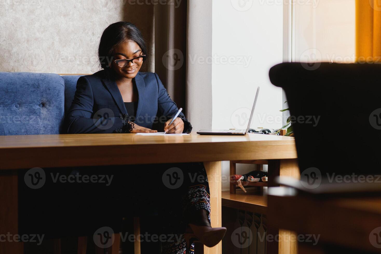 Hard work ensures success. Concentrated young African women working on laptop while sitting at working place photo