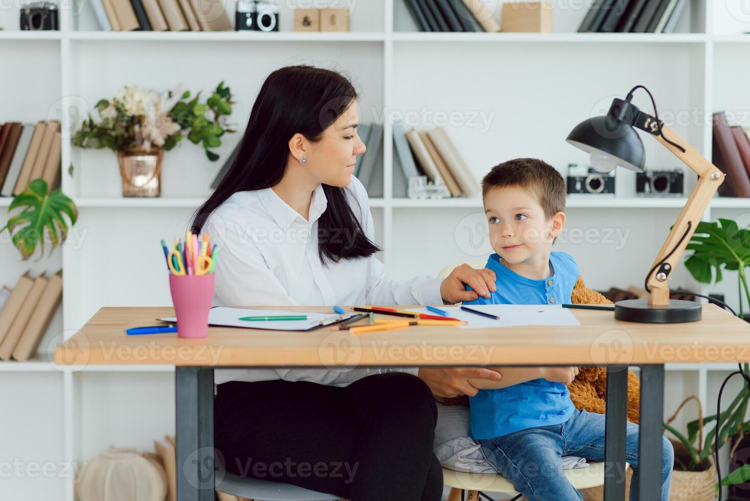 joven hembra psicólogo trabajando con pequeño chico en oficina foto