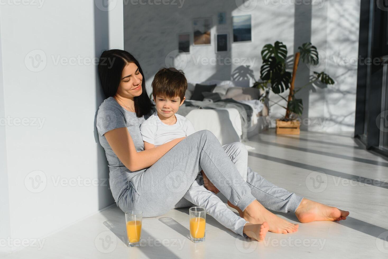 joven madre con su 4 4 años antiguo pequeño hijo vestido en pijama son relajante y jugando en el dormitorio a el fin de semana juntos, perezoso Mañana. foto