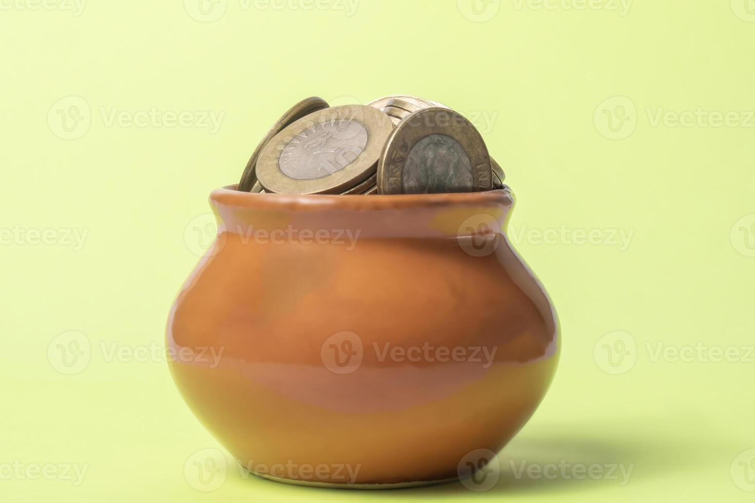 Coins in a clay pot on a green background. Money saving concept. photo