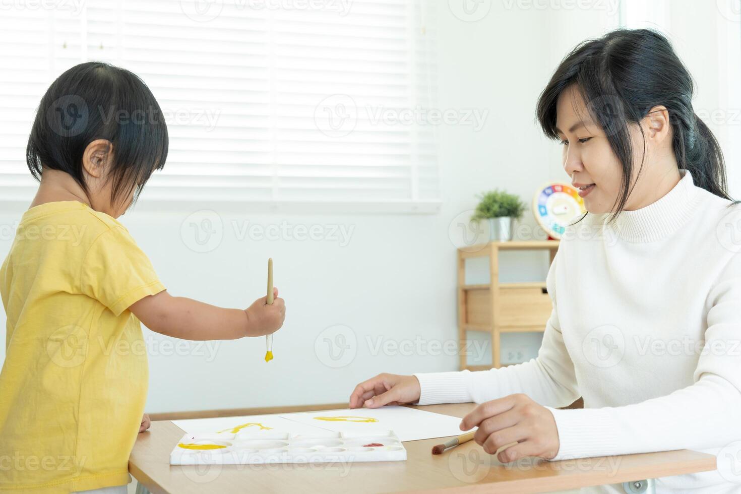 contento Asia madre jugando aprendizaje pintar para pequeño muchacha. gracioso familia es contento y emocionado en el casa. madre y hija teniendo divertido gasto hora juntos. día festivo, actividad foto