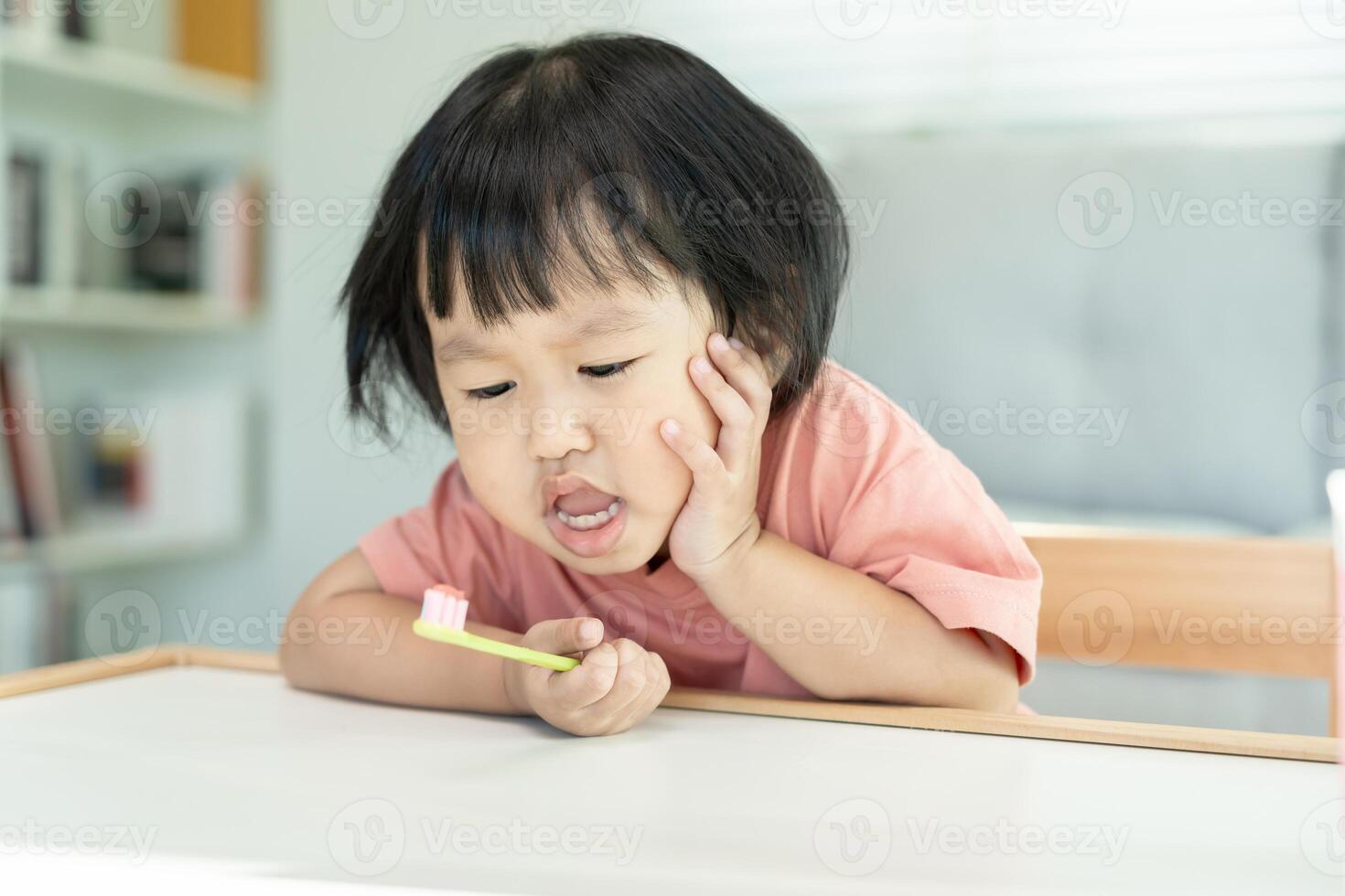 little asian girl presses hand to cheek, suffers from pain in tooth. Teeth decay, dental problems, child emotions and facial expression, oral health care, reducing sweets, fluorine coating photo