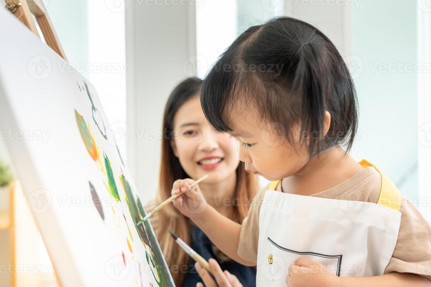 contento Asia madre jugando aprendizaje pintar para pequeño muchacha. gracioso familia es contento y emocionado en el casa. madre y hija teniendo divertido gasto hora juntos. día festivo, actividad foto