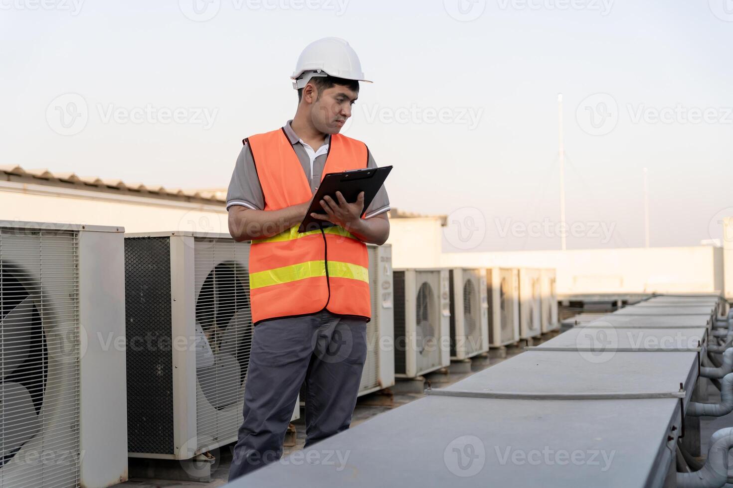 Asian maintenance engineer works on the roof of factory. contractor inspect compressor system and plans installation of air condition systems in construction. Checklist, inspector, control photo