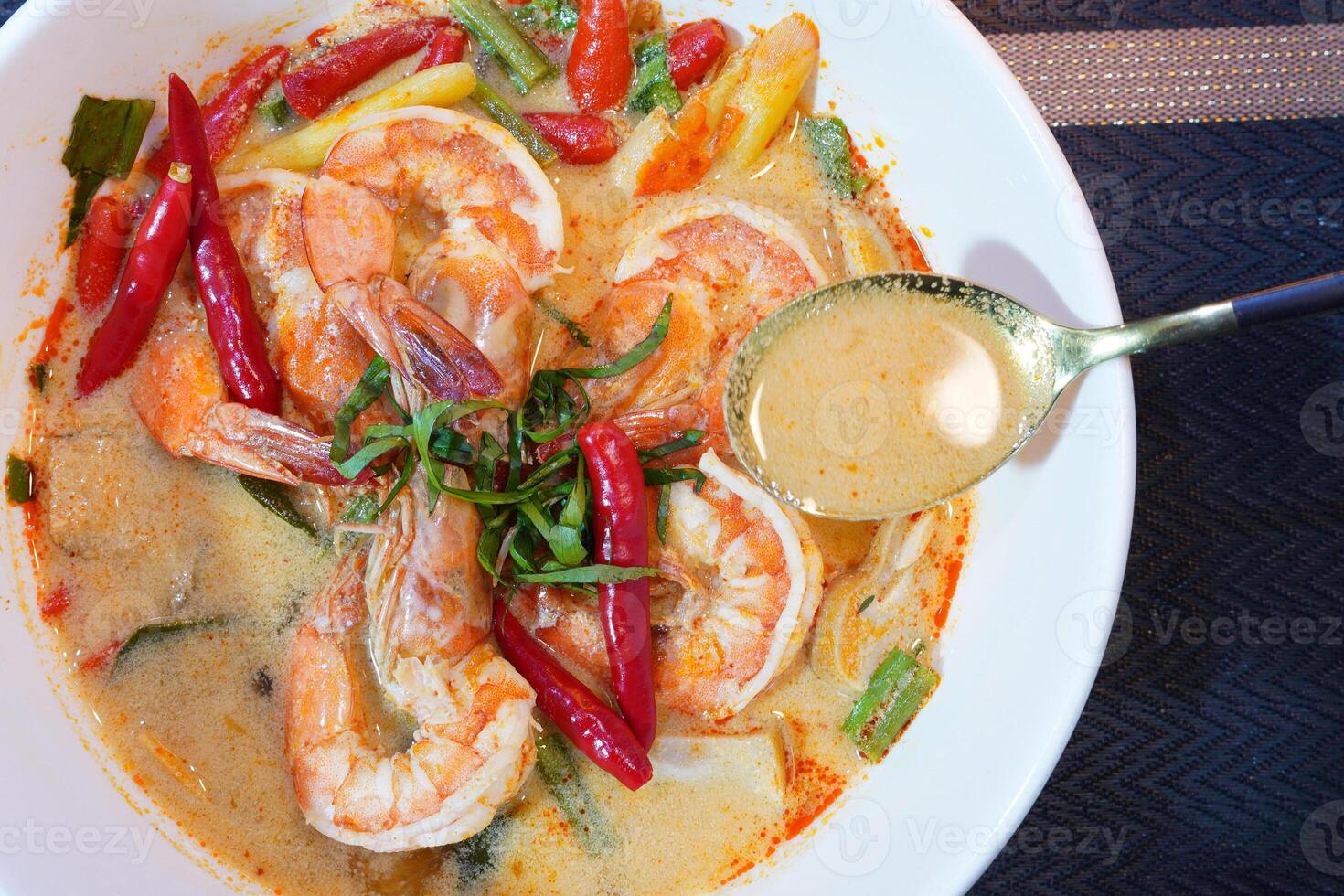 Tom Yam kung Spicy Thai soup with shrimp, seafood, coconut milk and chili in a bowl, close up photo