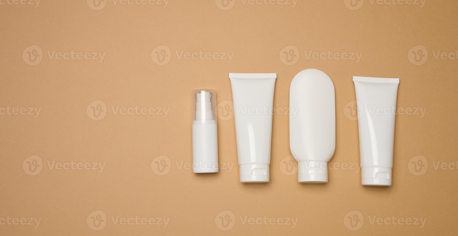 White plastic tubes, jars, and containers for cosmetic products on a brown background photo