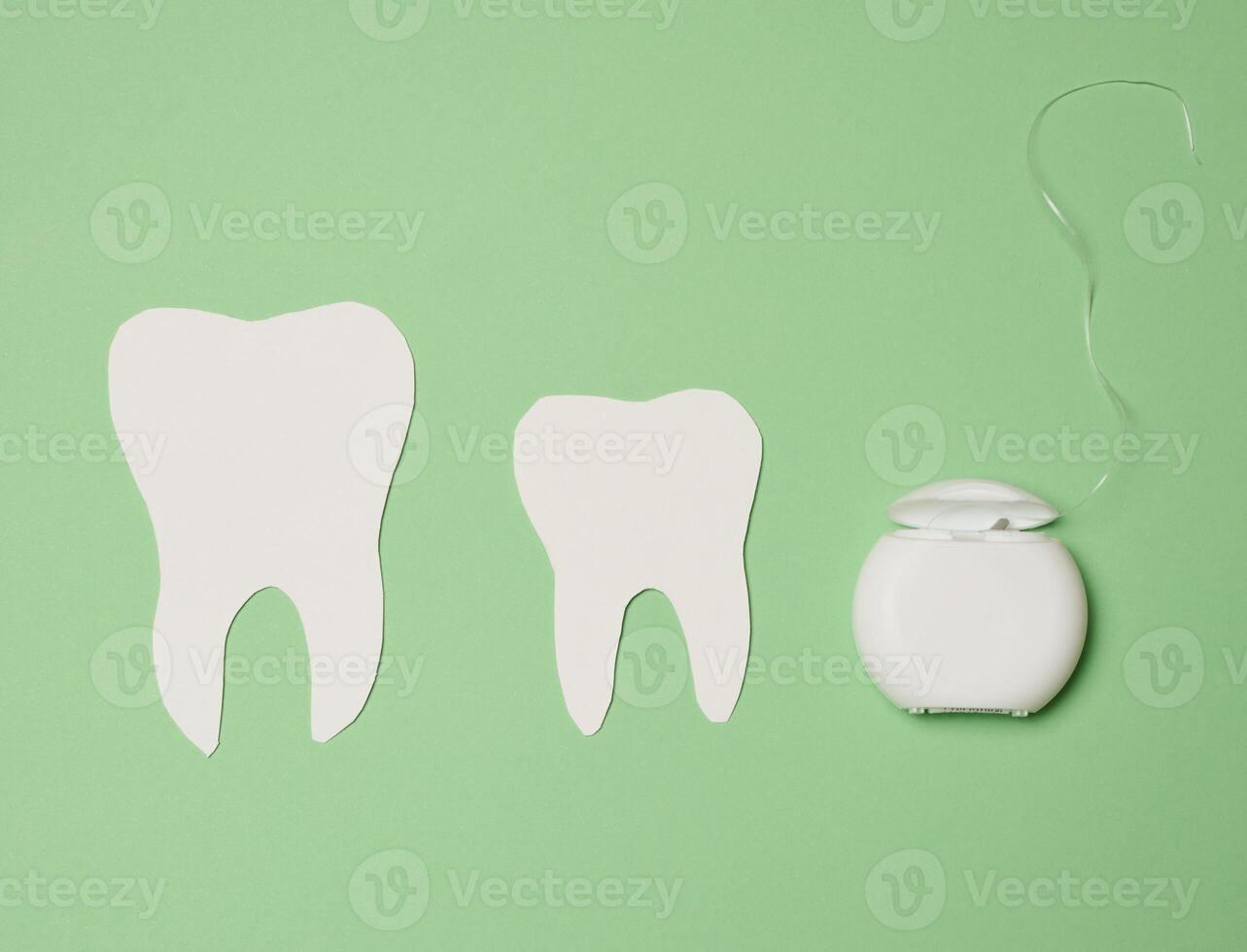 Dental floss and paper teeth on green background, oral hygiene photo