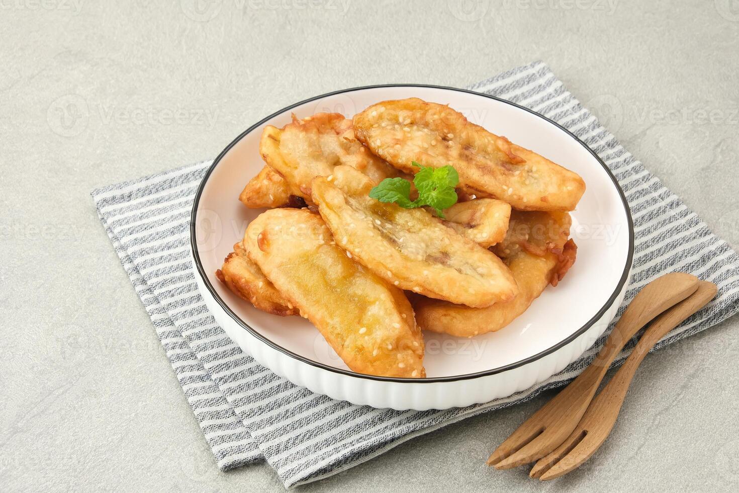 Pisang Goreng Wijen or banana fritters with sesame seed served in white plate. Indonesian food photo