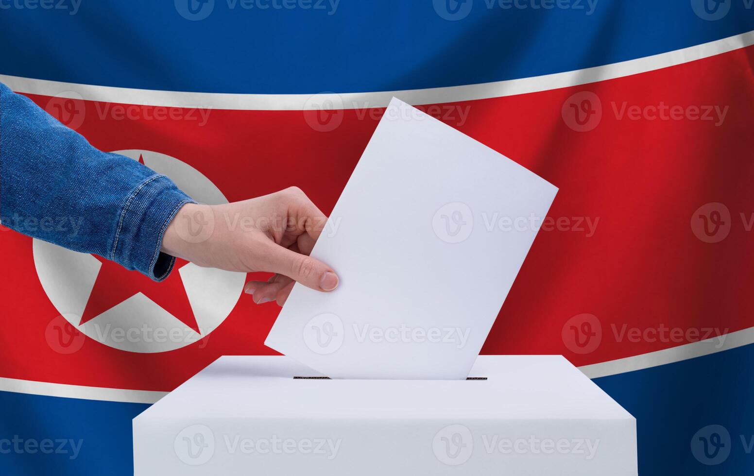 Elections in North Korea. The concept of voting. A hand throws a ballot into the ballot box. The flag of North Korea on the background. photo