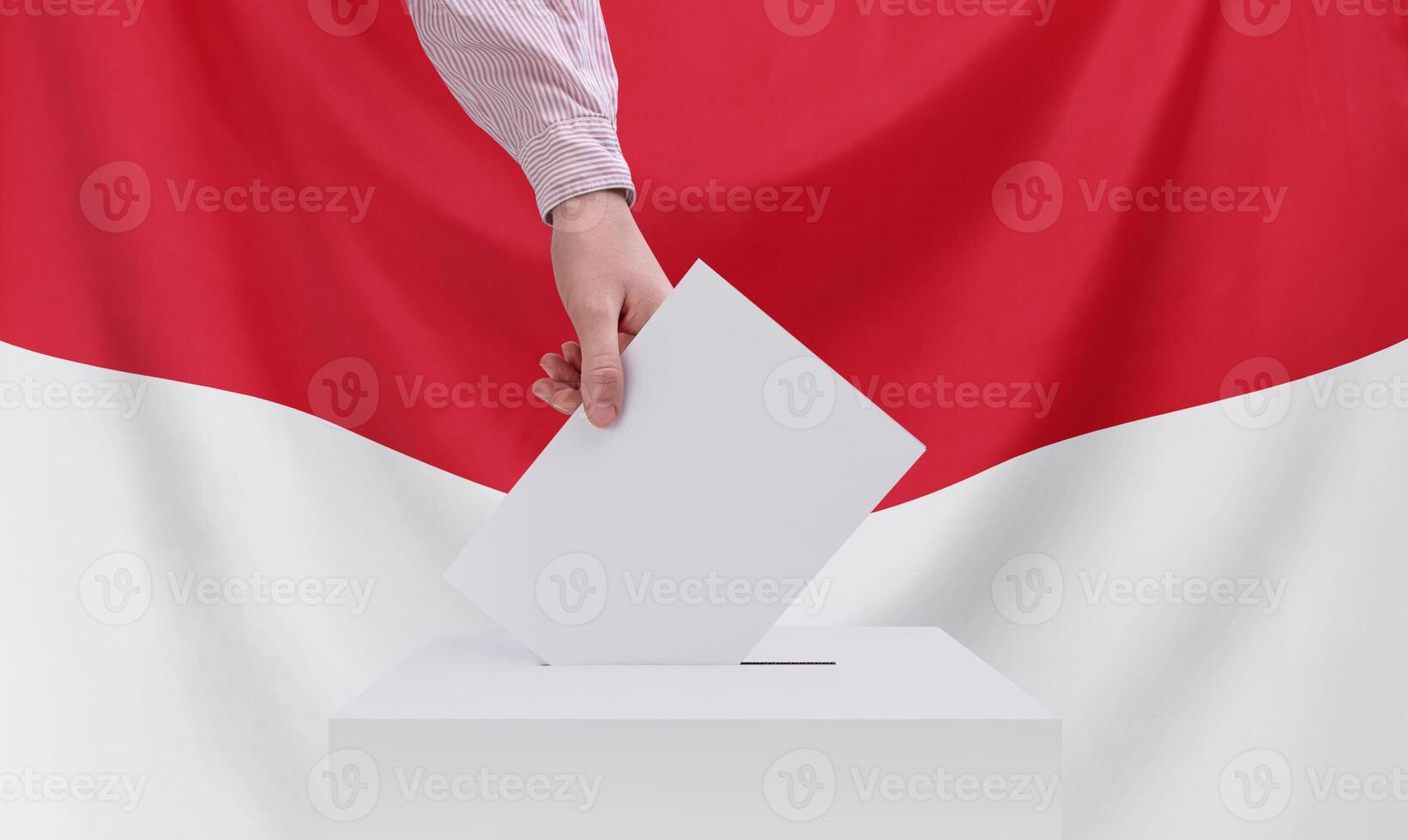 Elections, Indonesia. Election concept. A hand throws a ballot into the ballot box. Indonesia flag on background. photo