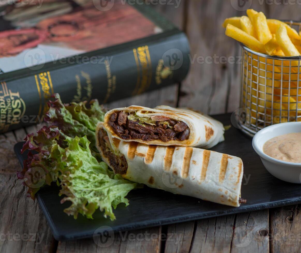 beef shawarma with fries isolated on cutting board side view of fastfood on wooden background photo
