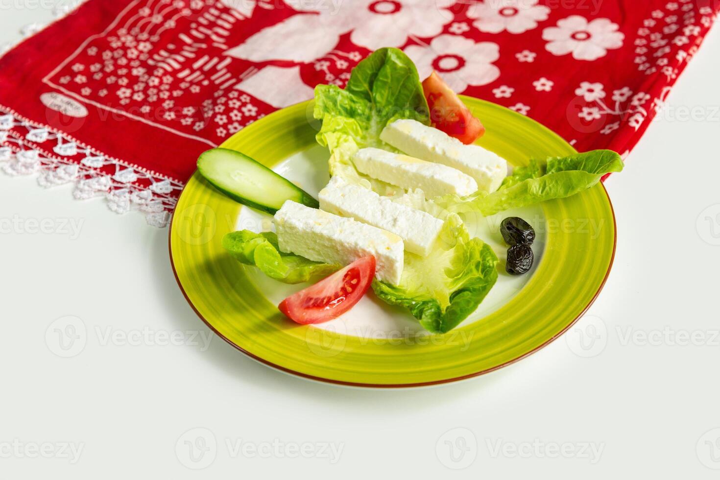 Traditional Turkish Cheese or Beyaz Peynir with cucumber and tomato in a dish isolated on colorful table cloth top view on grey background photo