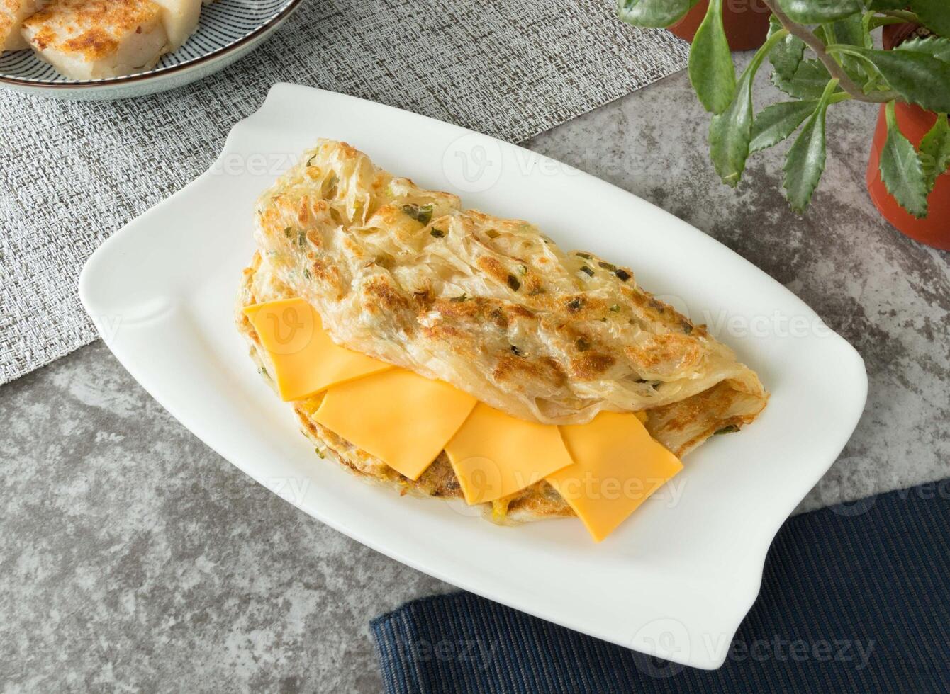 Cheese and egg onion pancake wrap served in dish isolated on napkin top view on table taiwan food photo