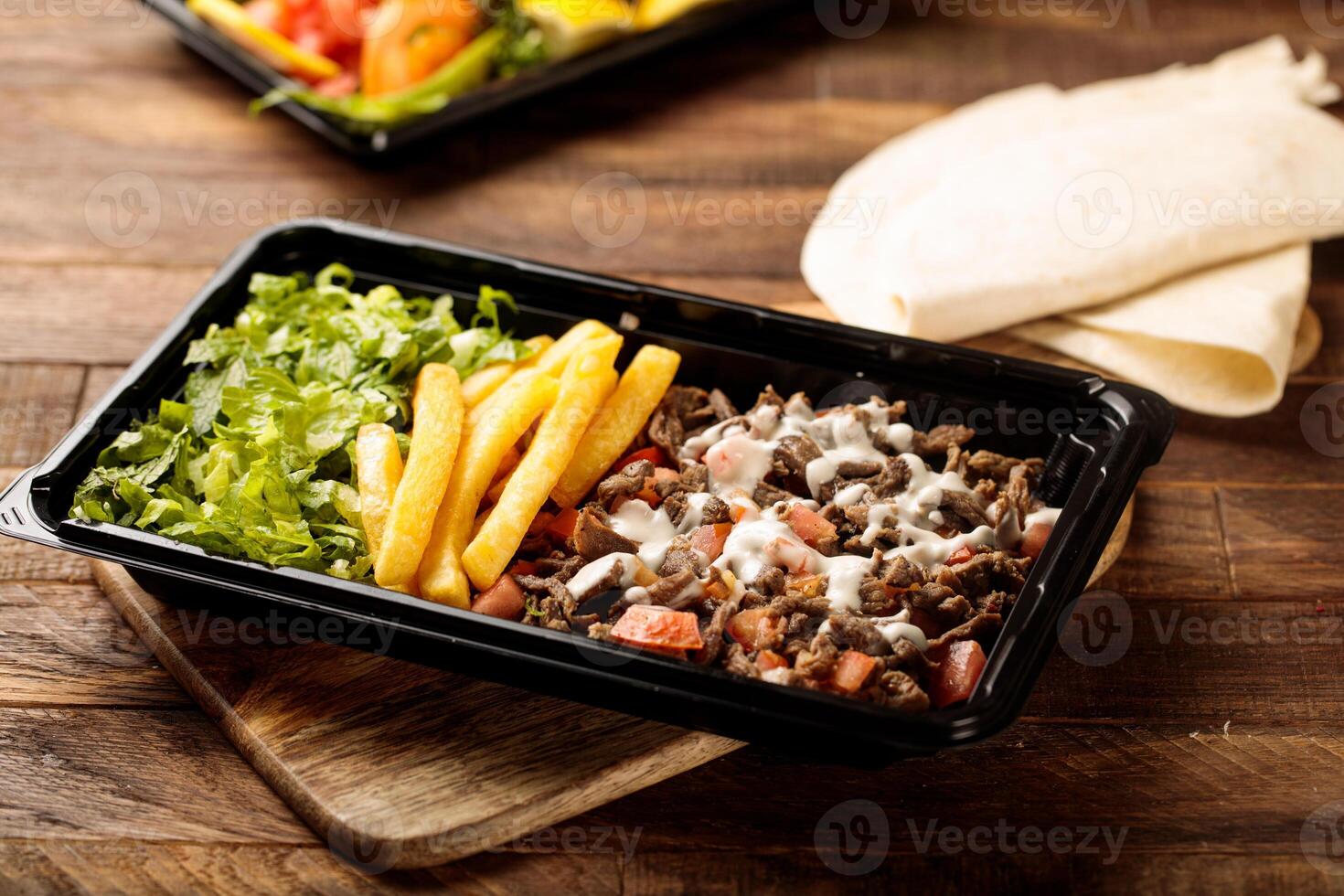 Beef Shawarma plate with salad, fries and pita bread served in a dish isolated on wooden table background side view of fastfood photo