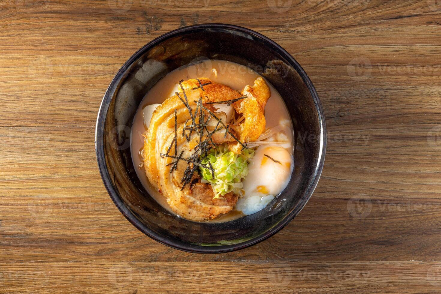 Chinese Crispy Porchetta with Noodles Pork Bone Broth in a dish top view on dark wooden background photo