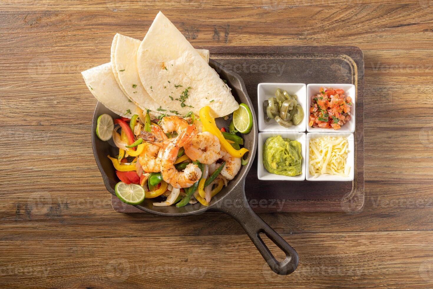Mexican prawn fajita with bell peppers, grilled vegetables and onions top view on dark wooden background photo