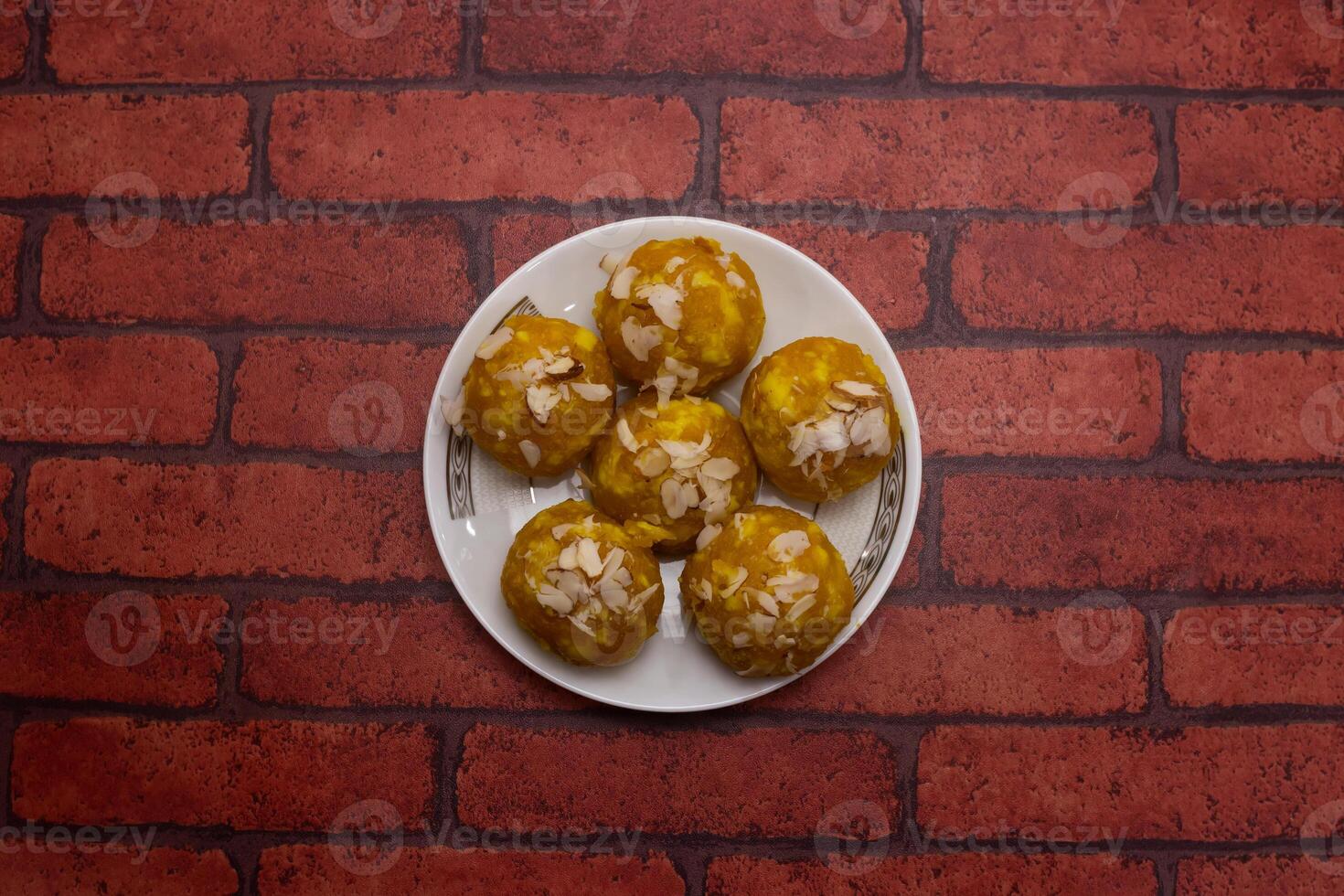 Mawa Laddu sweet topping with almonds served in plate isolated on background top view of bangladeshi dessert food photo