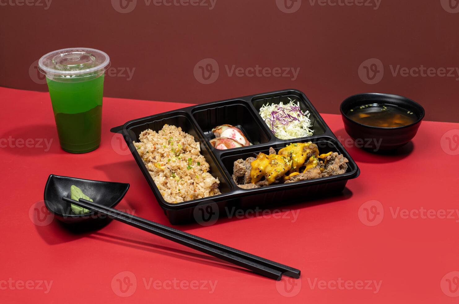 TORI KARAAGE PREMIUM BENTO with mint margarita, sauce and chopsticks isolated on red background side view of japanese fast food photo