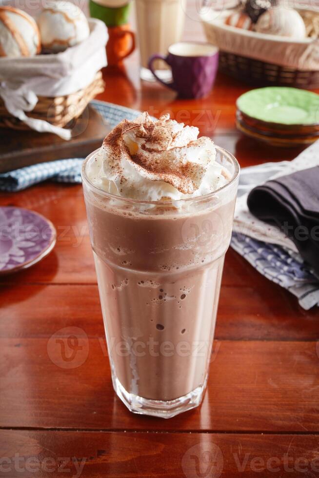 A glass of healthy fresh chocolate milkshake isolated on wooden background side view photo