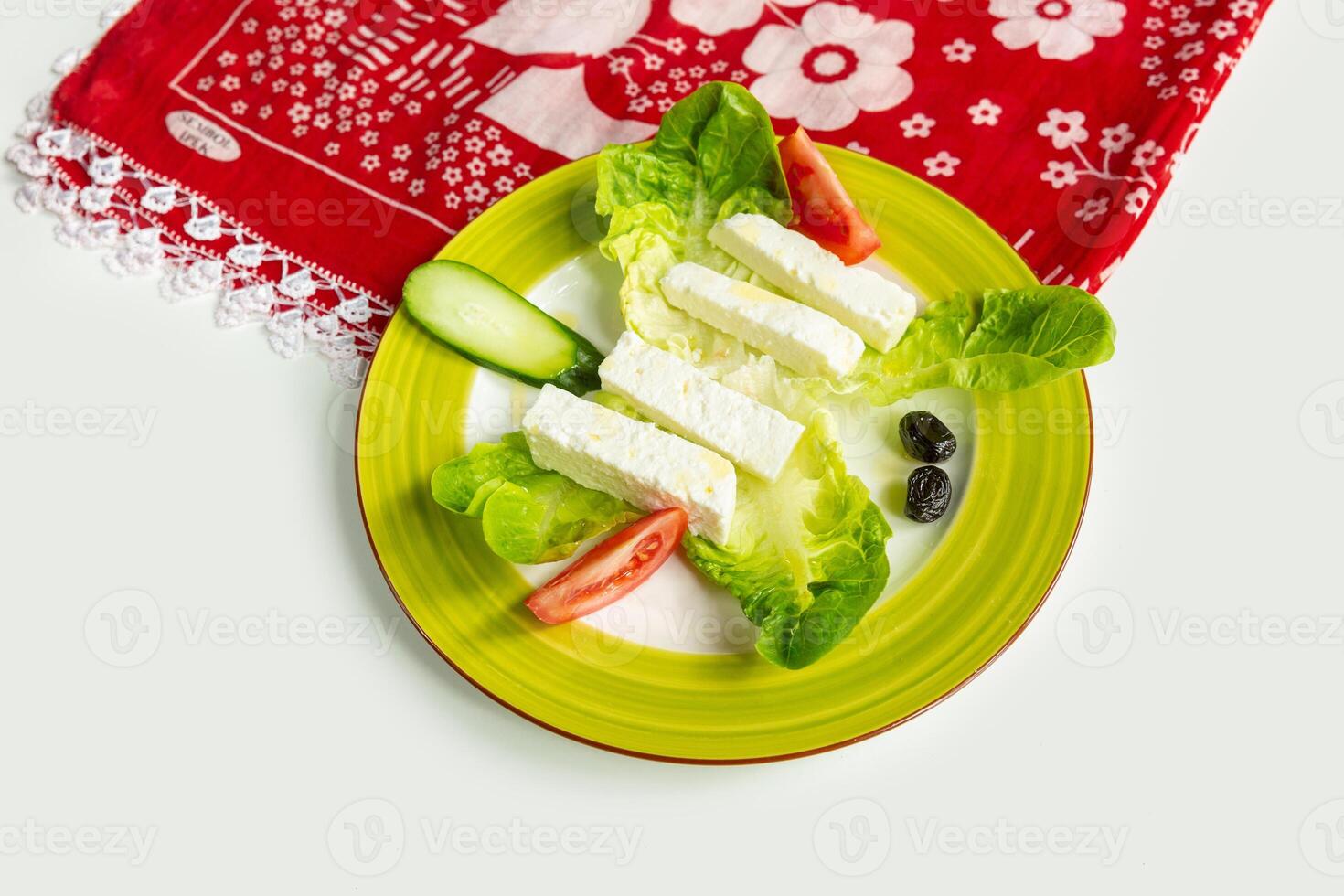 Traditional Turkish Cheese or Beyaz Peynir with cucumber and tomato in a dish isolated on colorful table cloth top view on grey background photo