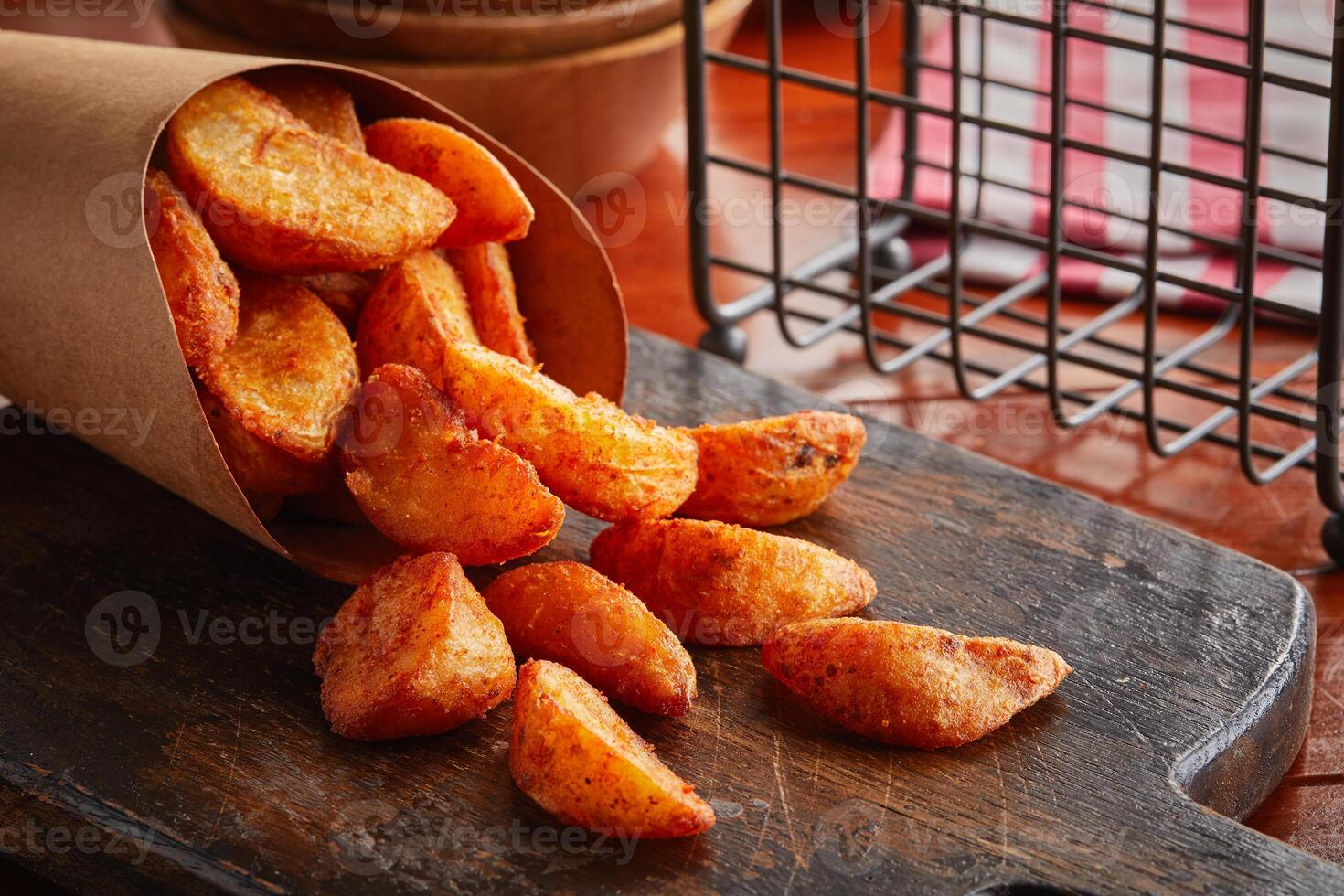 Potato Wedges served in a dish isolated on wooden background side view photo