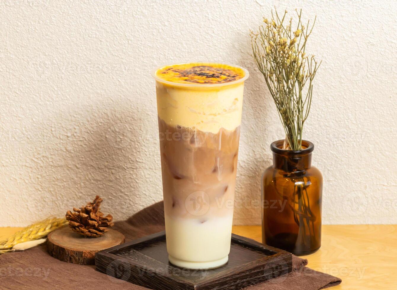 Iced Toasted Brulee Black Tea Latte served in disposable glass isolated on wooden board side view of taiwanese ice drink photo