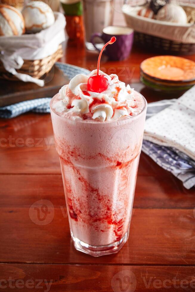 A jar of healthy fresh STRAWBERRY Milkshake with straw isolated on wooden background side view photo