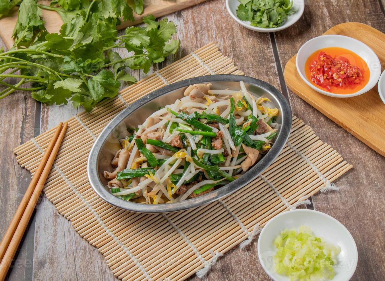Duck intestines mixed vegetables with chilli sauce, noodles, spoon and chopsticks served in dish isolated on napkin top view of hong kong food photo
