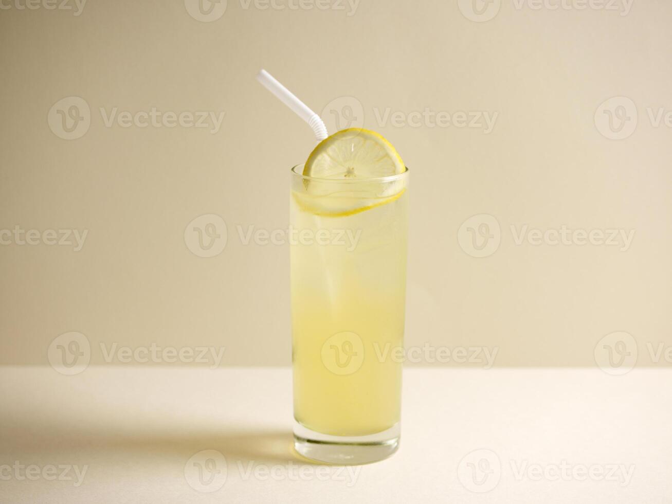 A glass of fresh iced honey lemon drink with straw isolated on grey background side view photo
