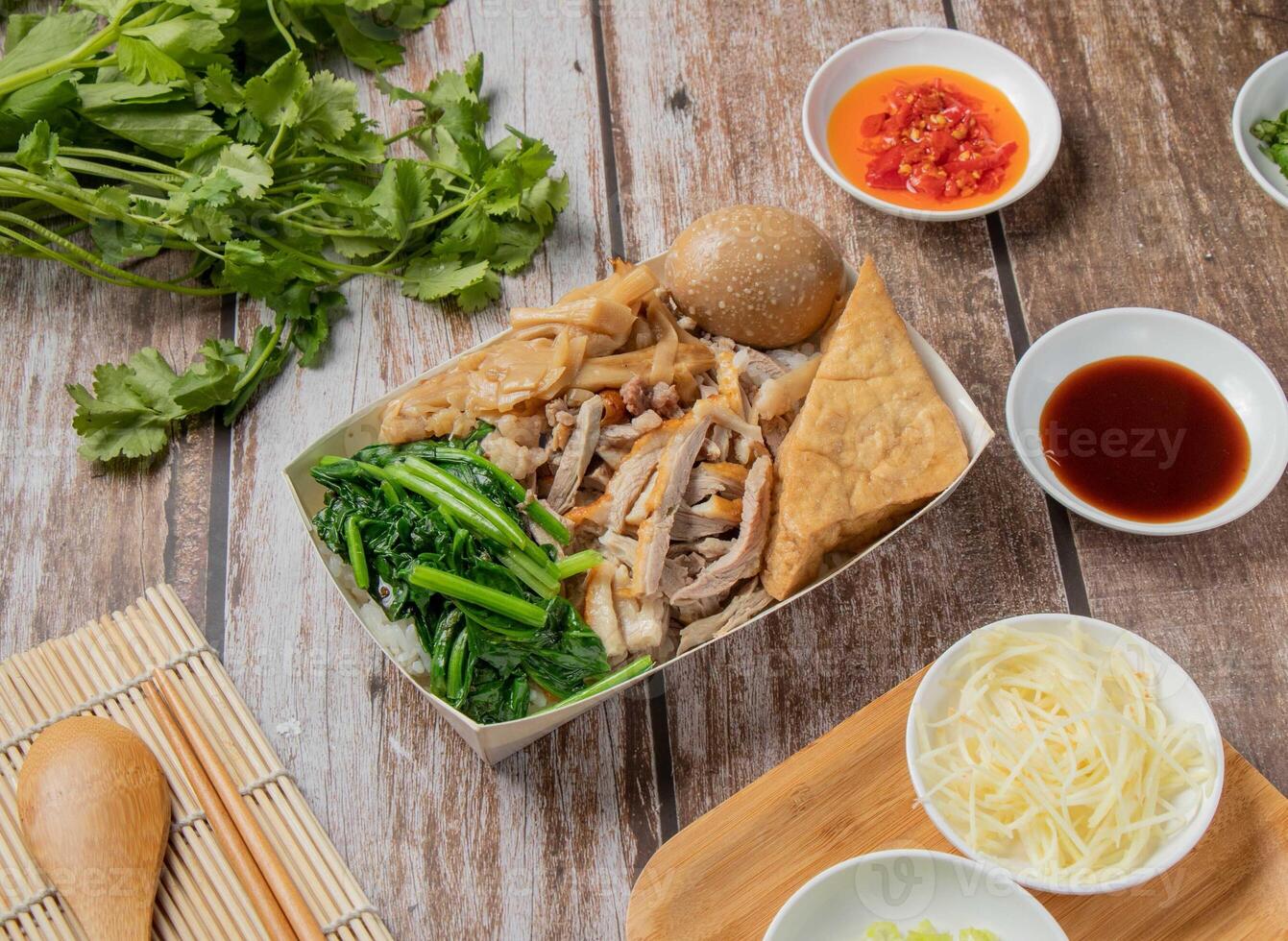 Duck meat bento include rice, braised duck, with chilli sauce, noodles, bread, toast, spoon and chopsticks served in dish isolated on napkin top view of hong kong food photo