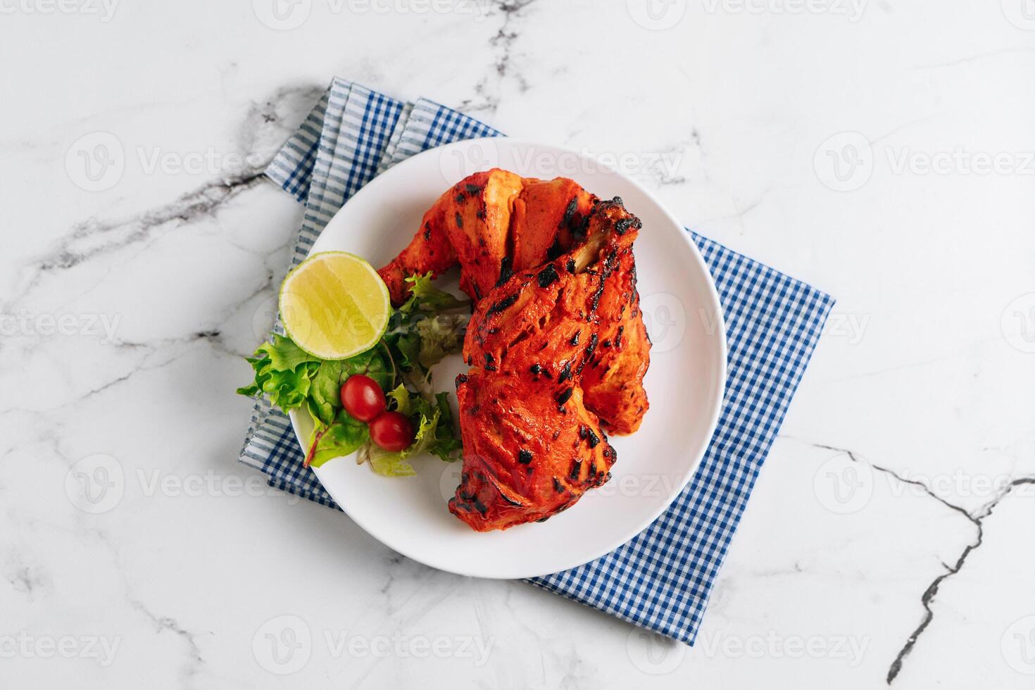 indian culture Tandoori chicken with lime in a dish isolated on napkin side view on grey background photo