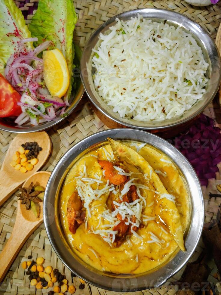 CHICKEN Mughlai with rice, salad and wooden spoon served in a dish isolated on table side view photo